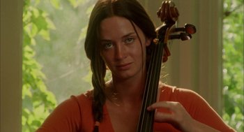 Movie still from “My Summer of Love” (2004), directed by Pawel Pawlikowski – A woman holding a cello in a room with trees in the background; Close Up shot, Over the shoulder angle
