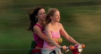 Movie still from “My Summer of Love” (2004), directed by Pawel Pawlikowski – Two young women riding bicycles on a green field; Medium shot, Low angle