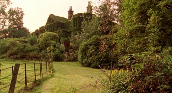 Movie still from “My Summer of Love” (2004), directed by Pawel Pawlikowski – A lush green garden with a large house in the background; Extreme Wide shot, Low angle