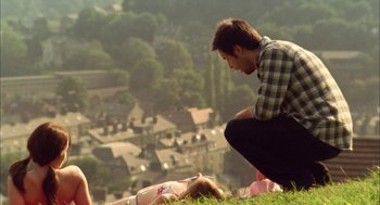Movie still from “My Summer of Love” (2004), directed by Pawel Pawlikowski – A man kneeling down next to a little girl laying in the grass; Wide shot, High angle