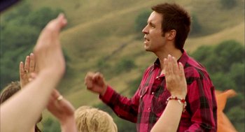 Movie still from “My Summer of Love” (2004), directed by Pawel Pawlikowski – A man in a plaid shirt clapping with people; Medium shot, Low angle