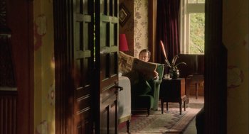 Movie still from “My Summer of Love” (2004), directed by Pawel Pawlikowski – A man sitting in a chair reading a newspaper; Wide shot, High angle