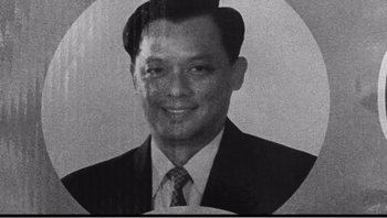 Movie still from “Mysterious Object at Noon” (2000), directed by Apichatpong Weerasethakul – An old black and white photo of a man wearing a suit and tie; Extreme Close Up shot, High angle