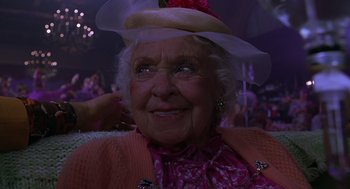 Movie still from “Mystery Men” (1999), directed by Kinka Usher – An older woman wearing a hat and a pink dress; Close Up shot, Low angle