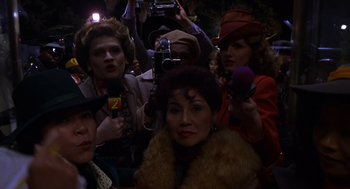 Movie still from “Mystery Men” (1999), directed by Kinka Usher – A group of people standing around a crowd of people; Close Up shot, High angle