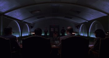 Movie still from “Mystery Men” (1999), directed by Kinka Usher – A group of people sitting in a room; Extreme Wide shot, Low angle