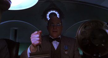 Movie still from “Mystery Men” (1999), directed by Kinka Usher – An older man in a suit and tie holding an umbrella; Medium shot, Low angle