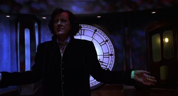 Movie still from “Mystery Men” (1999), directed by Kinka Usher – A man standing in front of a large clock; Medium shot, Low angle
