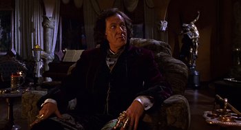 Movie still from “Mystery Men” (1999), directed by Kinka Usher – A man sitting on a couch in a living room; Medium shot, Low angle