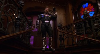 Movie still from “Mystery Men” (1999), directed by Kinka Usher – A man dressed in a costume standing on the stairs; Wide shot, Low angle