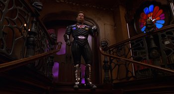 Movie still from “Mystery Men” (1999), directed by Kinka Usher – A man dressed in a costume standing on the stairs; Wide shot, Low angle