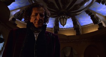 Movie still from “Mystery Men” (1999), directed by Kinka Usher – A man with long curly hair wearing a black jacket; Medium shot, Low angle