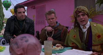 Movie still from “Mystery Men” (1999), directed by Kinka Usher – Three people sitting at a table with a plate of food on it; Medium shot, Low angle