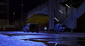 Movie still from “Mystery Men” (1999), directed by Kinka Usher – Two cars driving down a street at night; Extreme Wide shot, Low angle