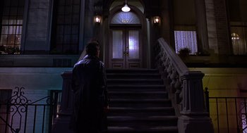 Movie still from “Mystery Men” (1999), directed by Kinka Usher – A man standing in front of a door way; Wide shot, Low angle