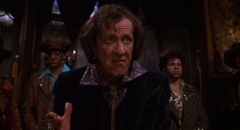 Movie still from “Mystery Men” (1999), directed by Kinka Usher – An older man in a black jacket and some other people; Close Up shot, Over the shoulder angle