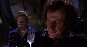 Movie still from “Mystery Men” (1999), directed by Kinka Usher – A man holding a fork in front of another man; Close Up shot, Over the shoulder angle