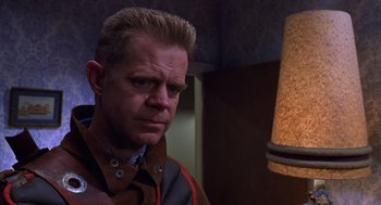 Movie still from “Mystery Men” (1999), directed by Kinka Usher – A person wearing a jacket near a lamp; Close Up shot, Low angle