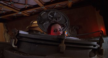 Movie still from “Mystery Men” (1999), directed by Kinka Usher – A woman with red eye makeup holding a hammer; Medium shot, Low angle