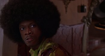 Movie still from “Mystery Men” (1999), directed by Kinka Usher – A man with a black afro is sitting in a chair; Close Up shot, Low angle