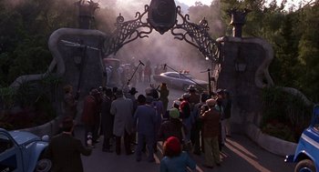 Movie still from “Mystery Men” (1999), directed by Kinka Usher – A group of people standing around a gate; Wide shot, High angle