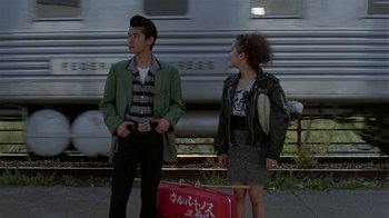 Movie still from “Mystery Train” (1989), directed by Jim Jarmusch – A man and a woman standing next to each other near a train; Medium shot, Low angle