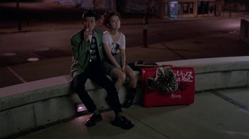 Movie still from “Mystery Train” (1989), directed by Jim Jarmusch – A man and a woman sitting next to each other on a bench; Wide shot, High angle