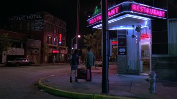 Movie still from “Mystery Train” (1989), directed by Jim Jarmusch – Two people walking on the sidewalk at night with luggage; Wide shot, Low angle