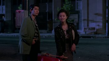 Movie still from “Mystery Train” (1989), directed by Jim Jarmusch – A man and a woman standing next to each other on a street; Medium shot, Over the shoulder angle