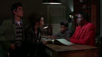 Movie still from “Mystery Train” (1989), directed by Jim Jarmusch – A group of people sitting around a table; Medium shot, Low angle