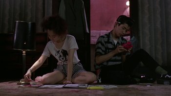 Movie still from “Mystery Train” (1989), directed by Jim Jarmusch – A man and a woman sitting on the floor; Medium shot, High angle