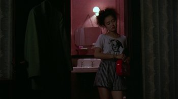 Movie still from “Mystery Train” (1989), directed by Jim Jarmusch – A woman standing in front of a mirror in a room; Medium shot, Over the shoulder angle