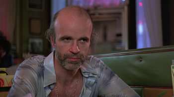 Movie still from “Mystery Train” (1989), directed by Jim Jarmusch – A man with a beard is sitting on a couch; Close Up shot, Low angle