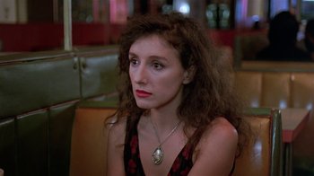 Movie still from “Mystery Train” (1989), directed by Jim Jarmusch – A woman sitting at a table with a necklace; Close Up shot, High angle