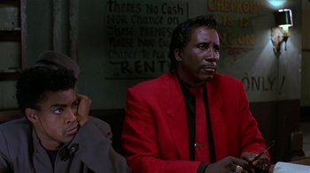 Movie still from “Mystery Train” (1989), directed by Jim Jarmusch – A man in a red jacket sitting next to another man in a black suit; Close Up shot, Low angle