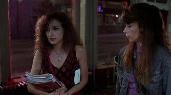 Movie still from “Mystery Train” (1989), directed by Jim Jarmusch – Two young women standing next to each other holding books; Medium shot, Over the shoulder angle