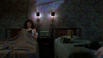 Movie still from “Mystery Train” (1989), directed by Jim Jarmusch – A woman reading a book in a bedroom; Wide shot, Overhead angle