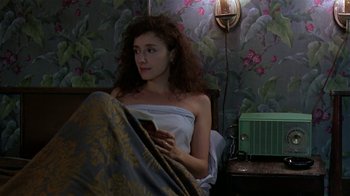 Movie still from “Mystery Train” (1989), directed by Jim Jarmusch – A woman sitting in a bed holding a cell phone; Medium shot, High angle