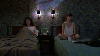 Movie still from “Mystery Train” (1989), directed by Jim Jarmusch – Two women sitting on a bed in a room; Wide shot, High angle