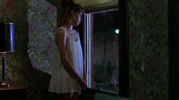 Movie still from “Mystery Train” (1989), directed by Jim Jarmusch – A woman in a white dress looking out of a window; Medium shot, Over the shoulder angle