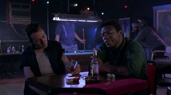 Movie still from “Mystery Train” (1989), directed by Jim Jarmusch – Two men sitting at a table in front of a pool table; Medium shot, Low angle