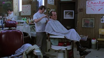 Movie still from “Mystery Train” (1989), directed by Jim Jarmusch – A man getting his hair cut in a barber shop; Medium shot, Low angle