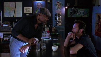 Movie still from “Mystery Train” (1989), directed by Jim Jarmusch – Two men sitting at a table in front of drinks; Medium shot, Over the shoulder angle