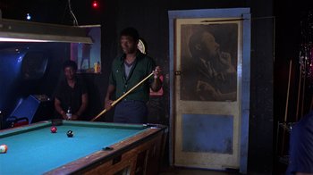 Movie still from “Mystery Train” (1989), directed by Jim Jarmusch – A man holding a pool stick in a room; Medium shot, Over the shoulder angle