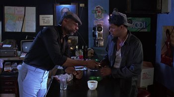 Movie still from “Mystery Train” (1989), directed by Jim Jarmusch – Two men sitting at a table in front of a phone; Medium shot, High angle