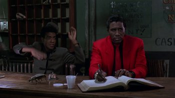 Movie still from “Mystery Train” (1989), directed by Jim Jarmusch – Two men sitting at a table with a book and a drink; Medium shot, Low angle