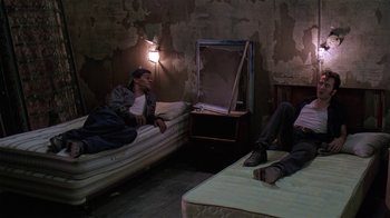 Movie still from “Mystery Train” (1989), directed by Jim Jarmusch – Two men are sitting on mattresses in a room; Wide shot, High angle