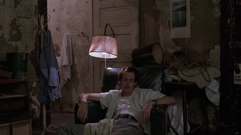 Movie still from “Mystery Train” (1989), directed by Jim Jarmusch – A man sleeping on a chair in a room; Medium shot, High angle