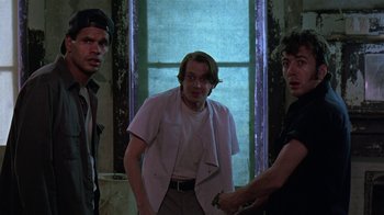 Movie still from “Mystery Train” (1989), directed by Jim Jarmusch – A group of men standing next to each other in front of a window; Medium shot, Low angle