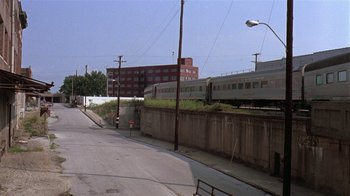 Movie still from “Mystery Train” (1989), directed by Jim Jarmusch – A train going down the tracks in the city; Extreme Wide shot, High angle